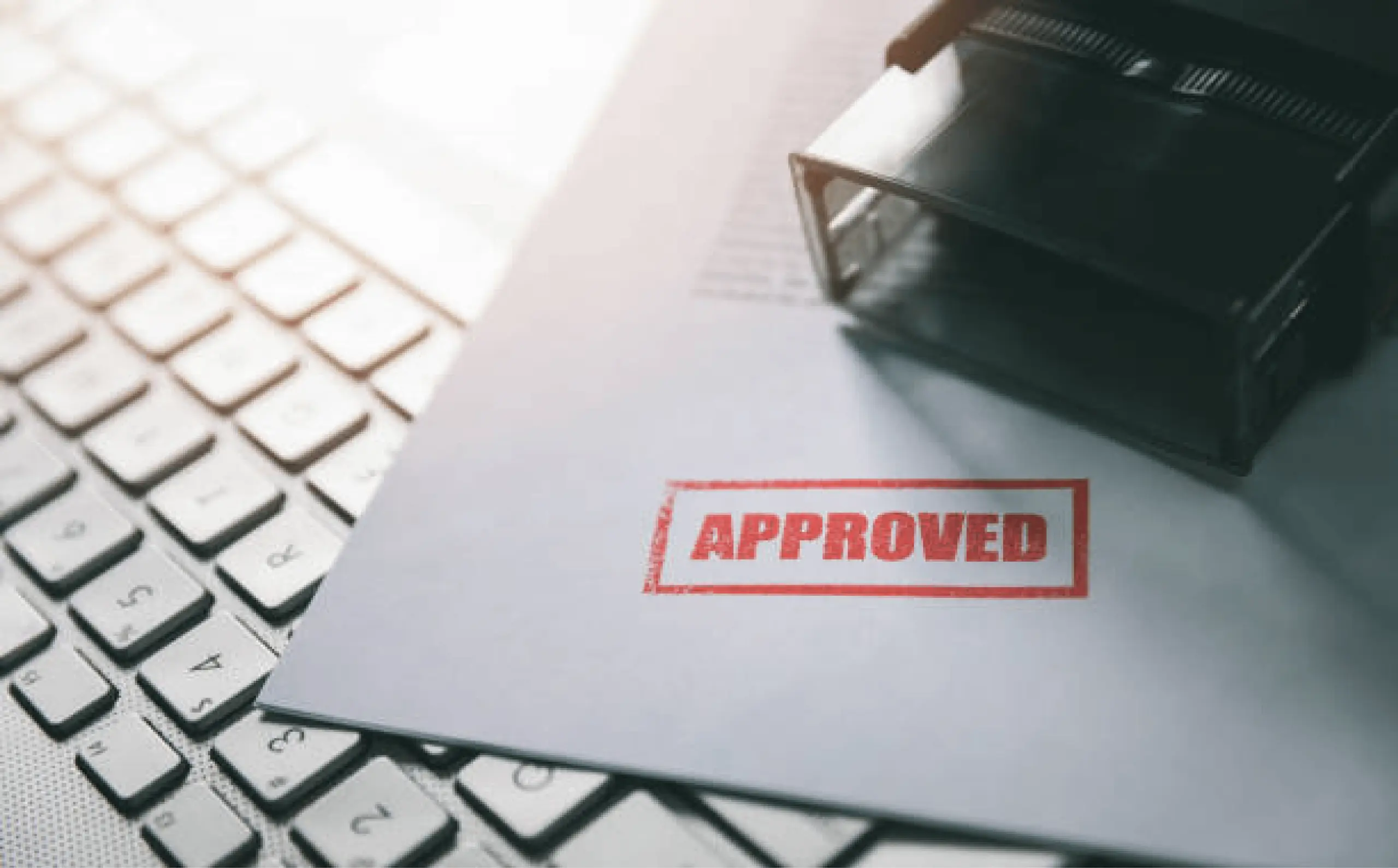 Approved stamp on document next to keyboard