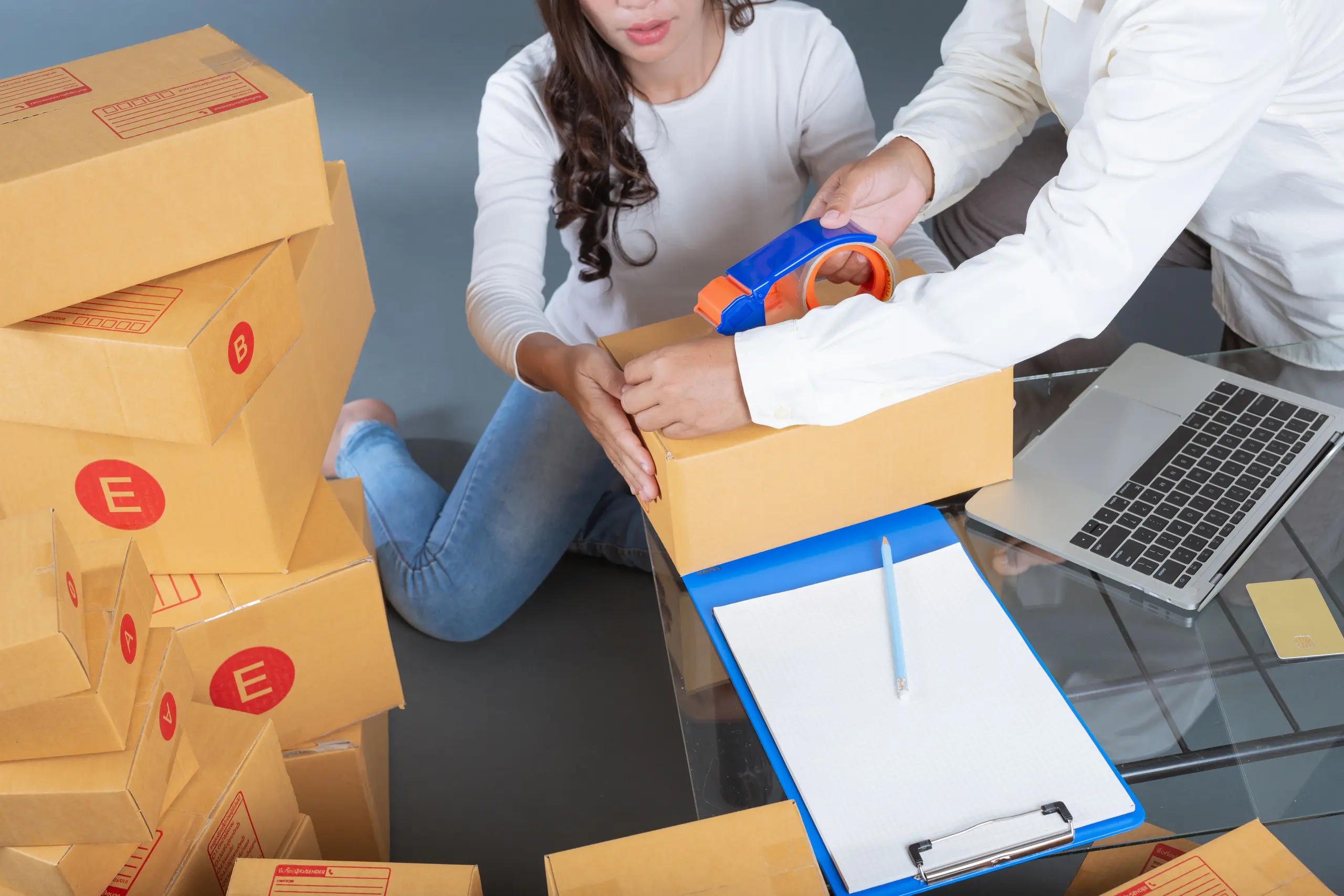 People packing boxes with laptop nearby