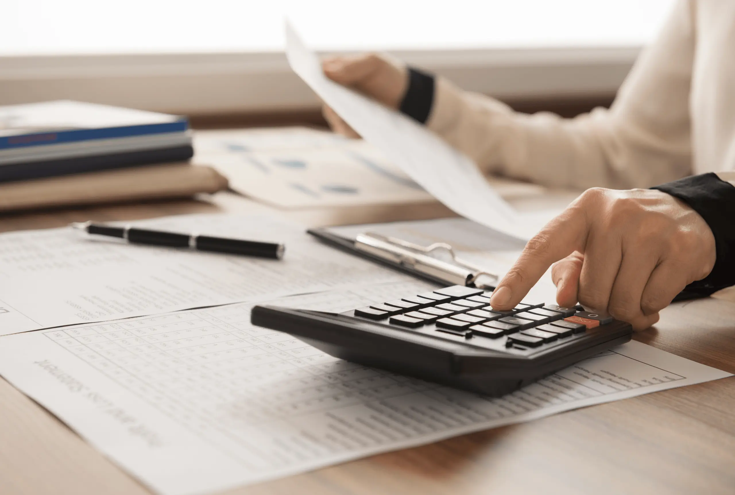 Person using calculator while reviewing documents