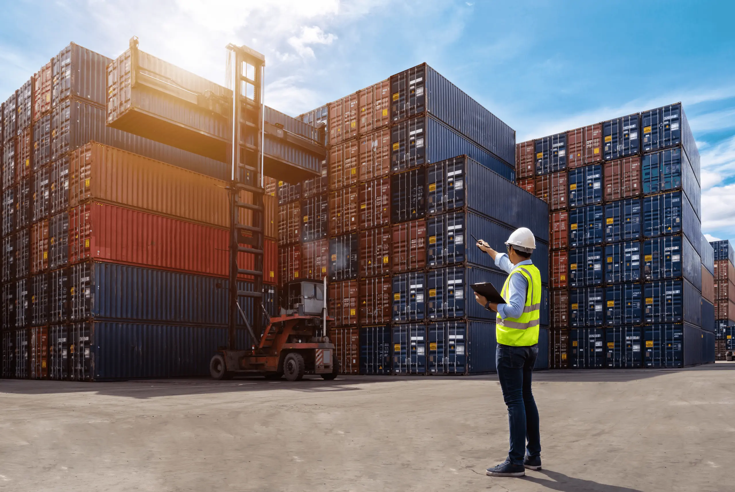 Worker in safety vest at shipping container yard